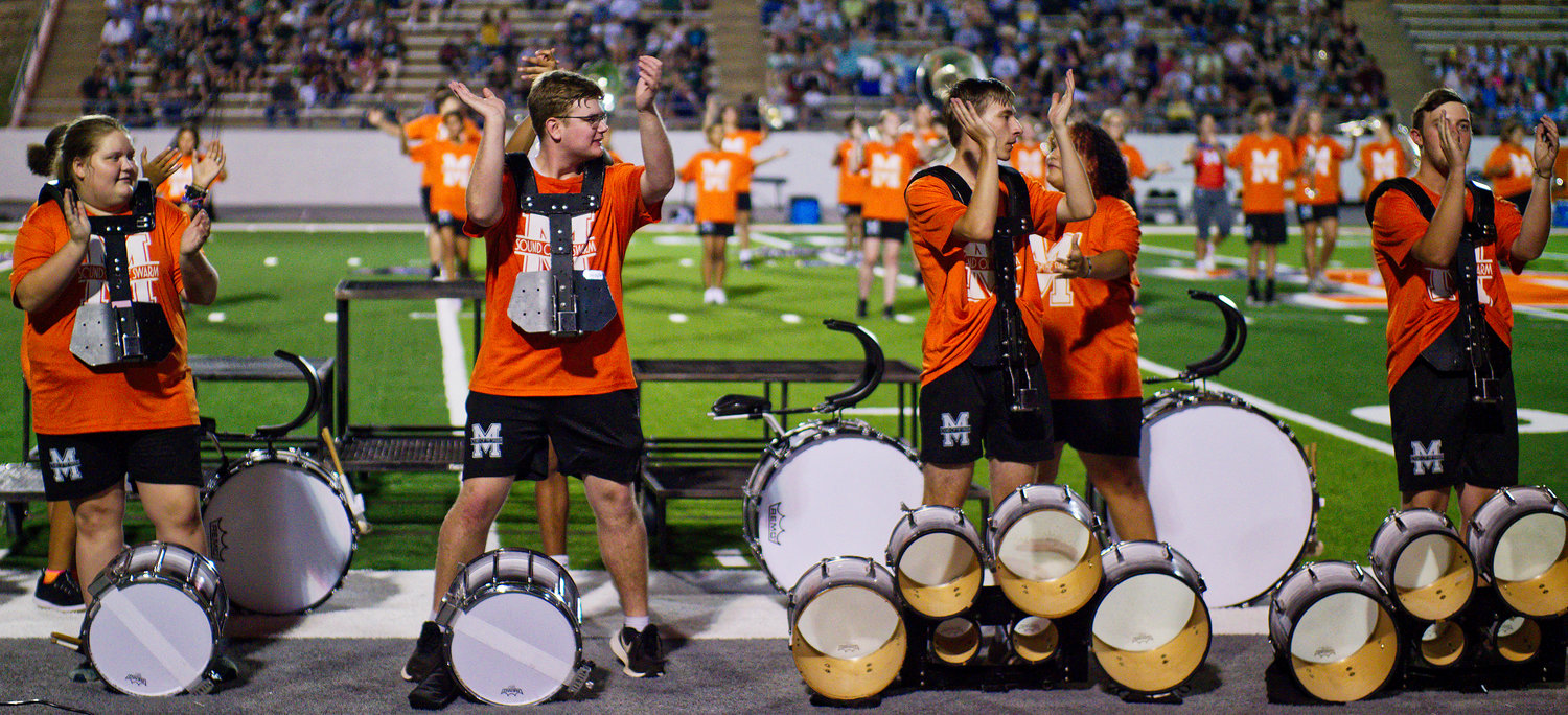 The Mineola High School Sound of the Swarm leads the crowd in “We Will Rock You" during its first halftime show of the new season. [find more football photos]